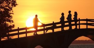 Photo of people standing on a bridge with the sunset in the background